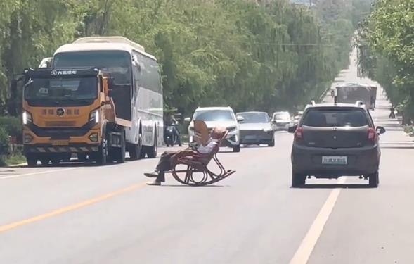 大爷躺马路中间晒太阳 车辆纷纷避让